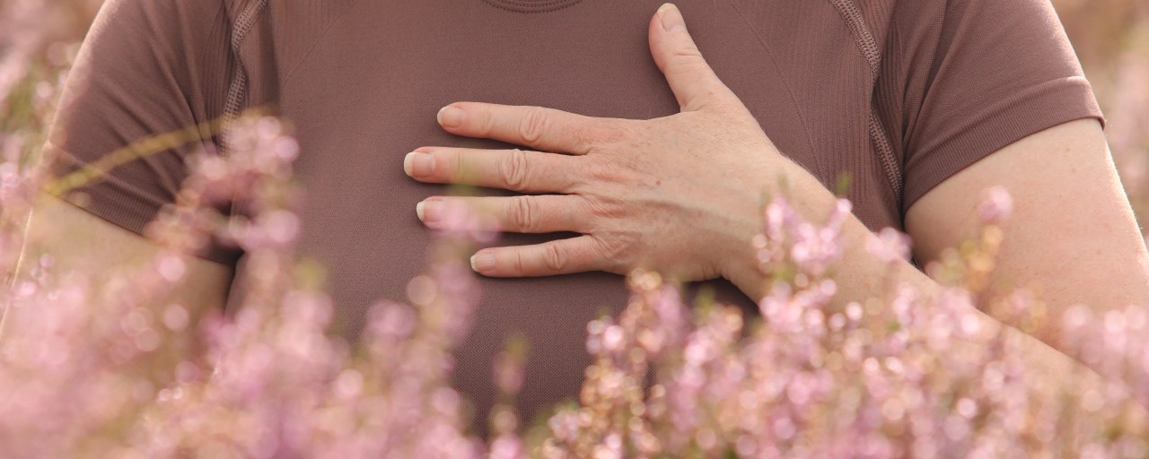 Een hand op het hart, zittend in de bloeiende heide