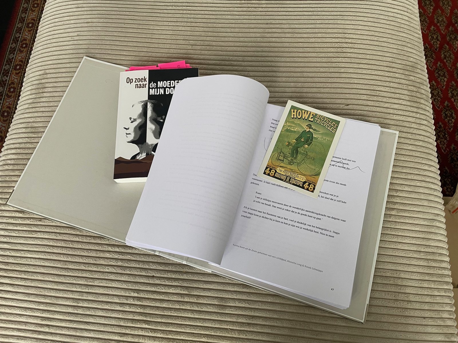 Het manuscript in de witte klapper, opengeslagen op bladzijde 47, met een oud ansichtkaartje als boekenlegger